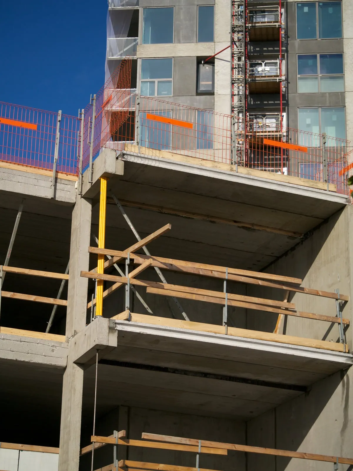 Etagebyggeri i beton under opførelse med stillads og afspærring